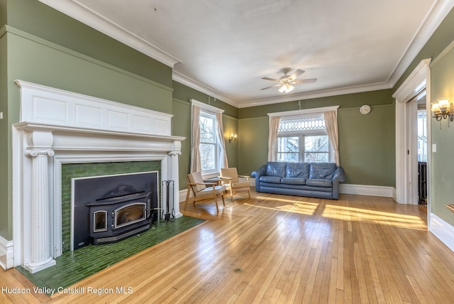 unfurnished living room featuring ceiling fan, ornamental molding, light hardwood / wood-style floors, and a wood stove