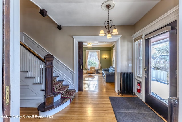 foyer entrance featuring radiator, an inviting chandelier, and light hardwood / wood-style floors