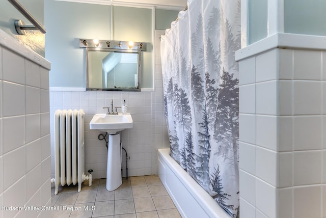 bathroom with tile patterned flooring, radiator, tile walls, and shower / bathtub combination with curtain