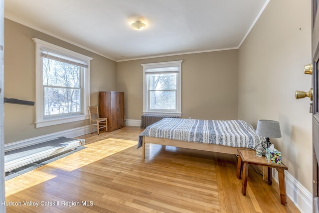 bedroom with crown molding, radiator heating unit, and light hardwood / wood-style floors