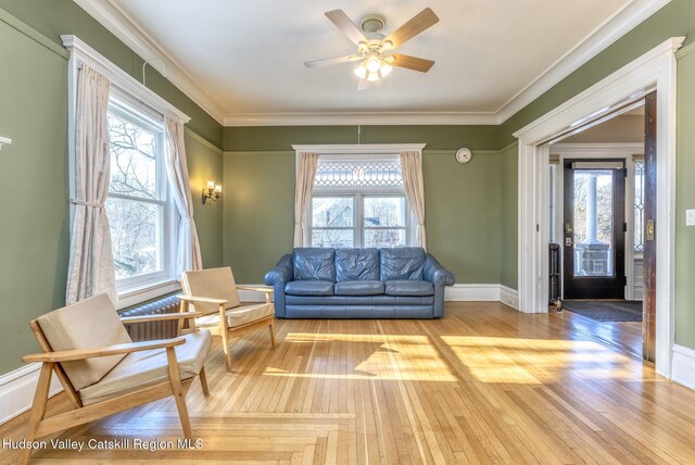 living room featuring crown molding, ceiling fan, and light wood-type flooring