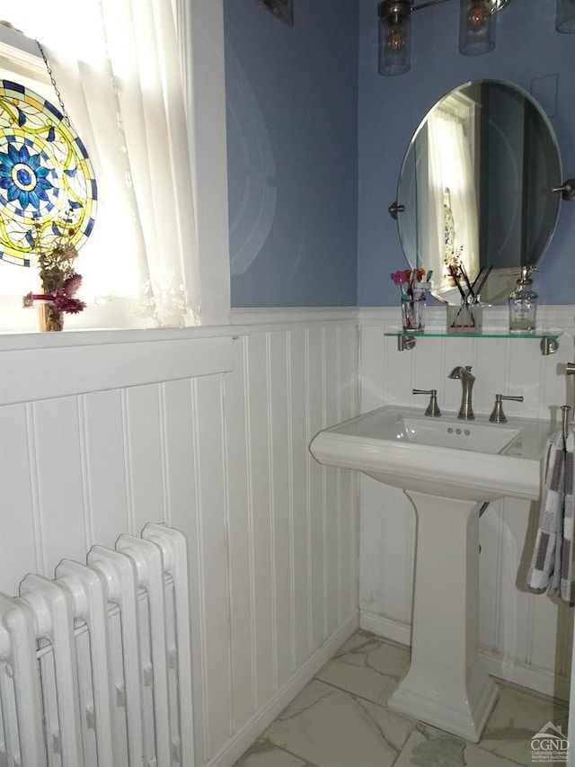 19 Aitken Ave, Hudson, NY 12534 - bathroom featuring radiator heating unit, marble look tile flooring, a wainscoted wall, a decorative wall, and a sink