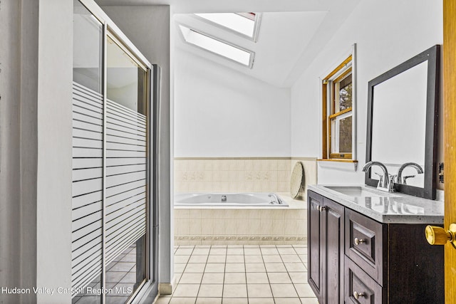 bathroom with tiled tub, lofted ceiling with skylight, tile patterned flooring, and vanity