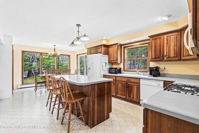 kitchen featuring pendant lighting, white appliances, a center island, and a wealth of natural light