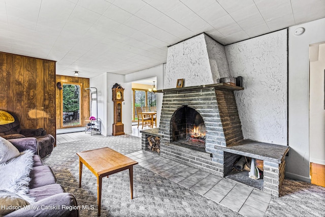 living room featuring baseboard heating, wooden walls, and a fireplace