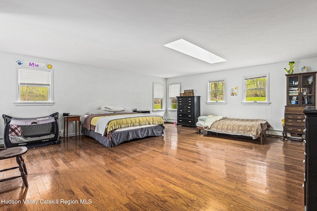 bedroom featuring wood-type flooring, multiple windows, and a baseboard heating unit