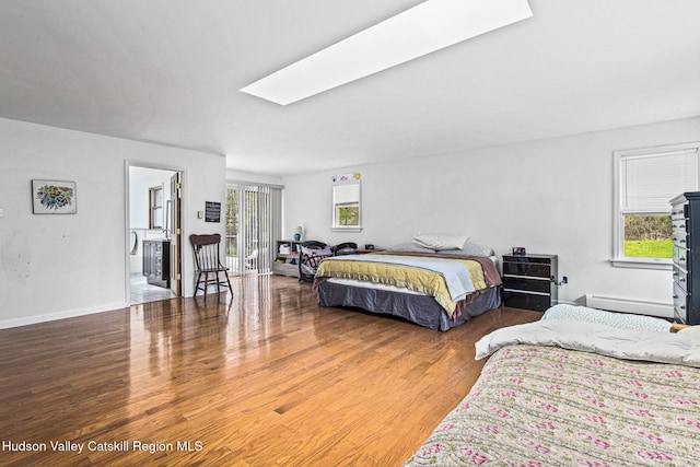 bedroom featuring a skylight, wood-type flooring, and a baseboard radiator