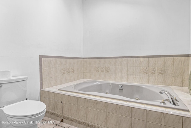 bathroom featuring tile patterned flooring, toilet, and tiled bath