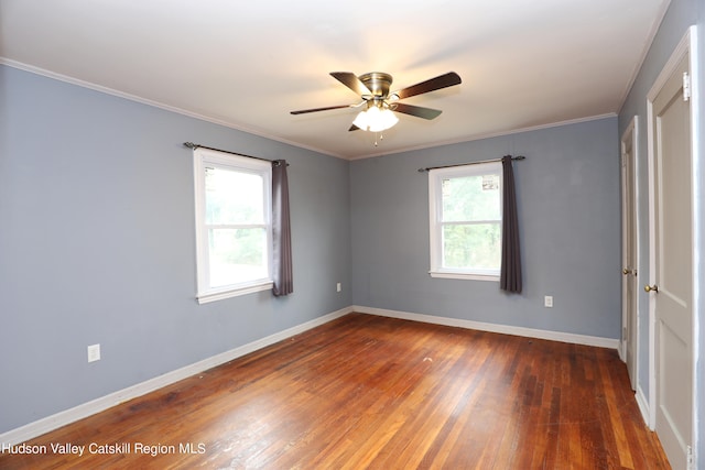 spare room featuring ornamental molding, dark wood-type flooring, ceiling fan, and a healthy amount of sunlight