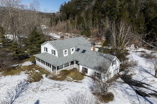 snowy aerial view featuring a wooded view