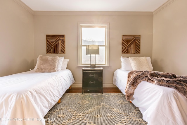 bedroom featuring baseboards, wood finished floors, and crown molding