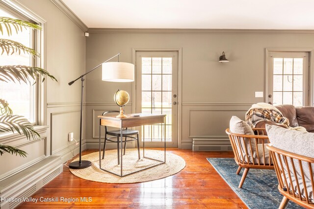 home office with a wealth of natural light, visible vents, wood finished floors, and crown molding