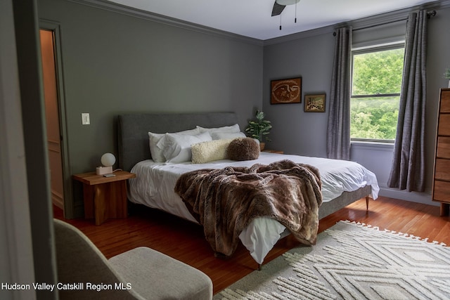 bedroom with ornamental molding, ceiling fan, and wood finished floors