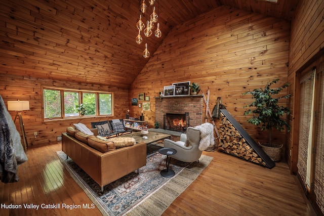 living area featuring wood-type flooring, high vaulted ceiling, a brick fireplace, and wooden walls