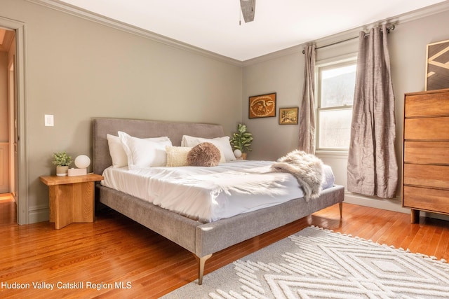 bedroom with crown molding and light wood-style flooring