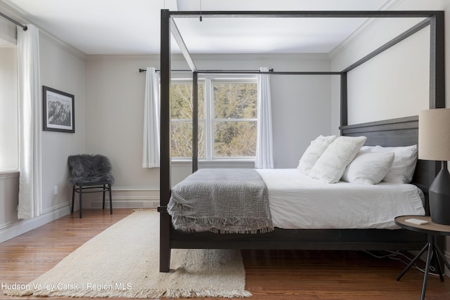 bedroom featuring ornamental molding, baseboards, and wood finished floors