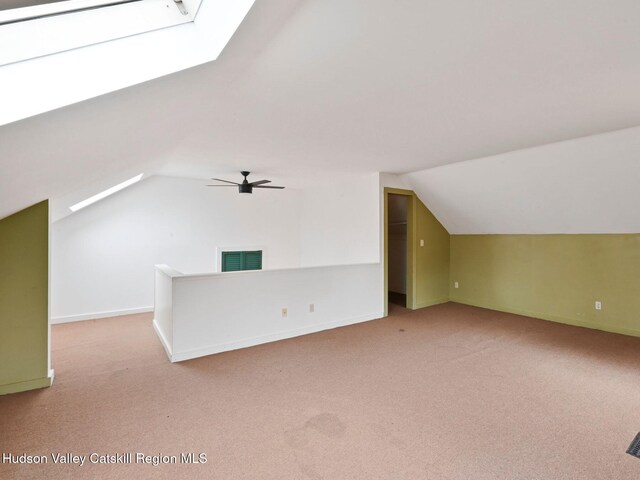 additional living space featuring ceiling fan, lofted ceiling with skylight, and light carpet