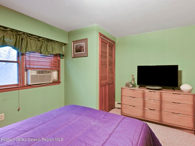 carpeted bedroom featuring baseboard heating, a closet, and cooling unit