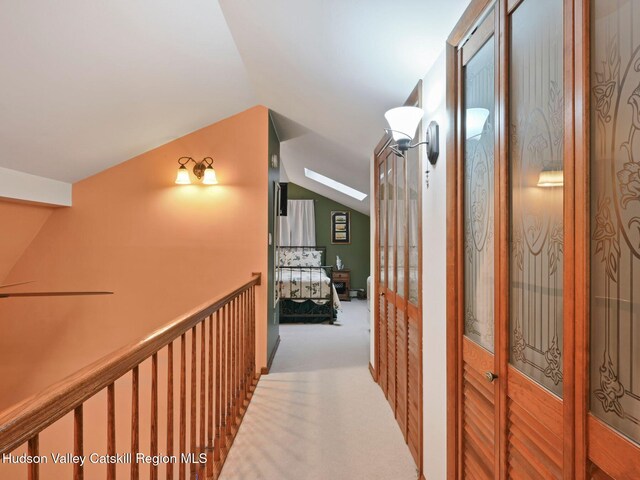 hall featuring light colored carpet and lofted ceiling