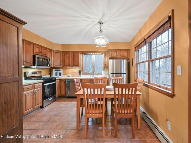 kitchen with hanging light fixtures, light tile patterned floors, baseboard heating, stainless steel appliances, and a chandelier