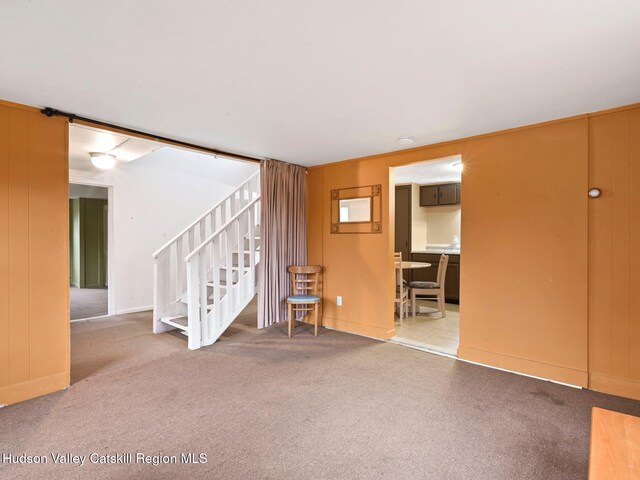 unfurnished living room featuring carpet flooring and wooden walls