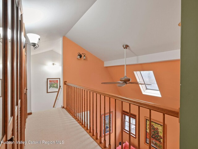 corridor with vaulted ceiling with skylight and carpet flooring