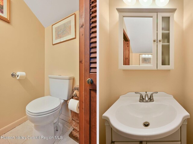 bathroom featuring toilet, tile patterned floors, lofted ceiling, and sink