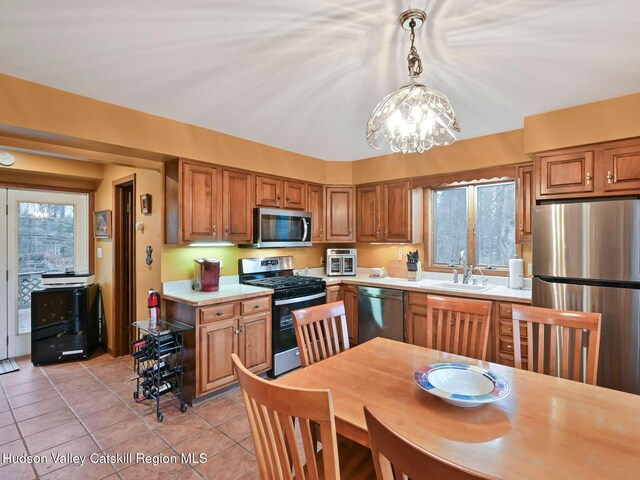 kitchen featuring plenty of natural light, sink, stainless steel appliances, and hanging light fixtures