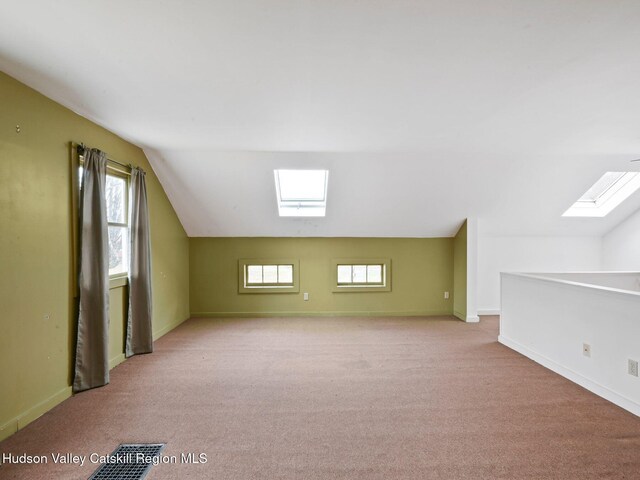 bonus room with lofted ceiling with skylight and light carpet