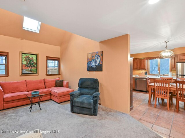 tiled living room featuring plenty of natural light, cooling unit, and vaulted ceiling with skylight