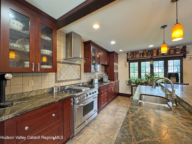 kitchen featuring reddish brown cabinets, wall chimney exhaust hood, appliances with stainless steel finishes, a sink, and backsplash