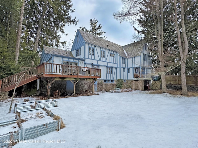 snow covered property featuring fence and a deck