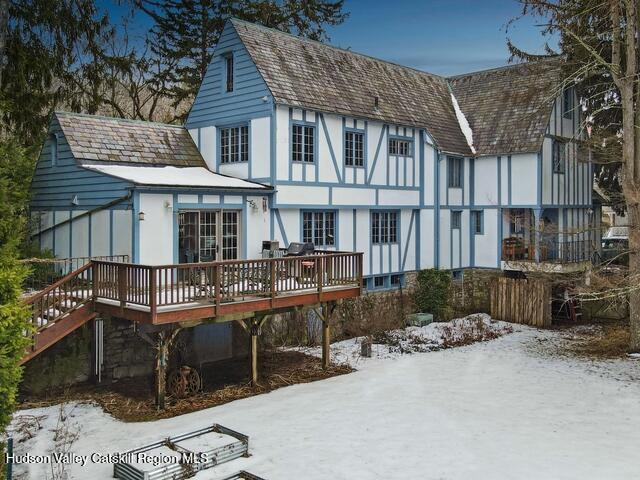 snow covered rear of property with a deck and stucco siding