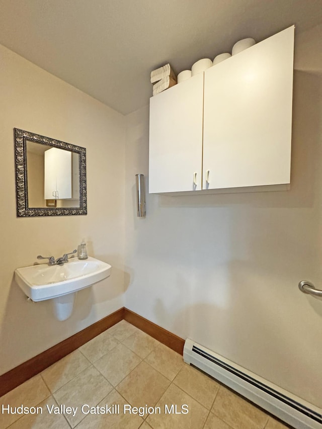 bathroom with a baseboard radiator, tile patterned flooring, a sink, and baseboards