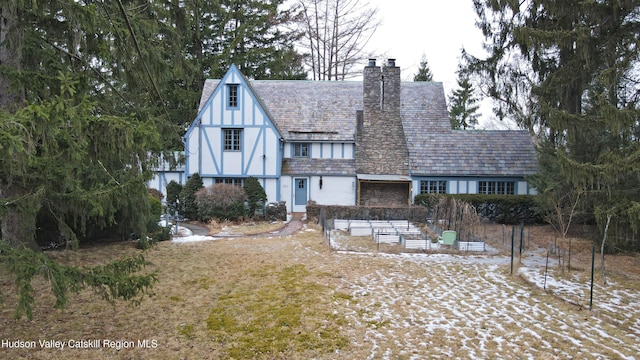 rear view of property with stone siding, a garden, a chimney, and stucco siding