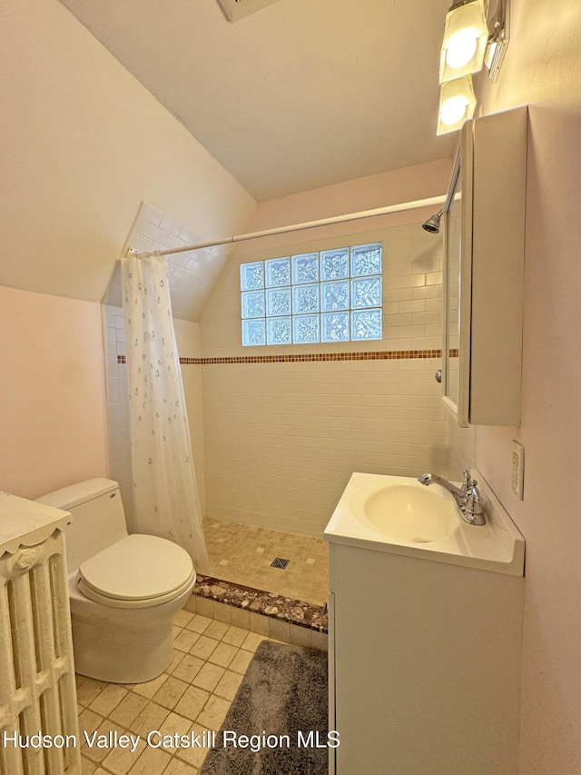 bathroom with tiled shower, toilet, tile patterned floors, vaulted ceiling, and vanity