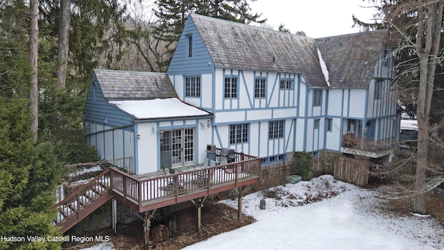 snow covered house with stucco siding and a wooden deck