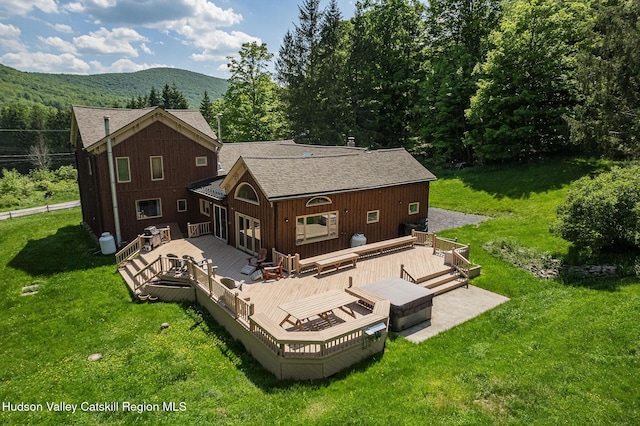 rear view of house with a yard, roof with shingles, and a deck with mountain view