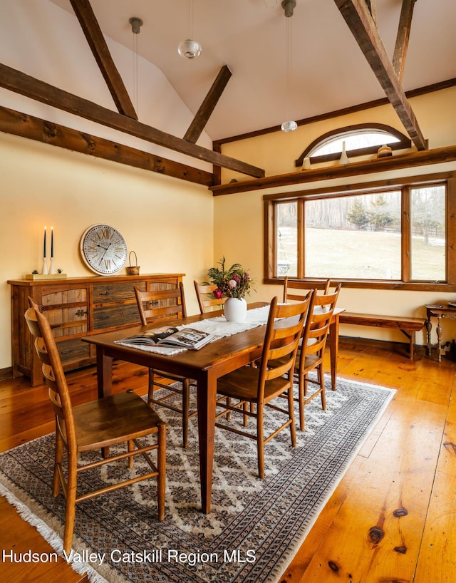 dining area featuring baseboards, wood-type flooring, and high vaulted ceiling