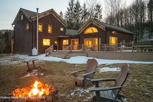 snow covered property with board and batten siding and an outdoor fire pit