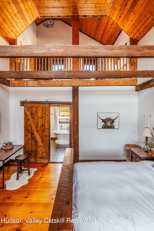 bedroom with a barn door, high vaulted ceiling, wooden ceiling, and hardwood / wood-style flooring