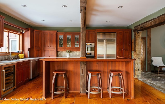 kitchen featuring wine cooler, appliances with stainless steel finishes, light wood-style floors, and a sink