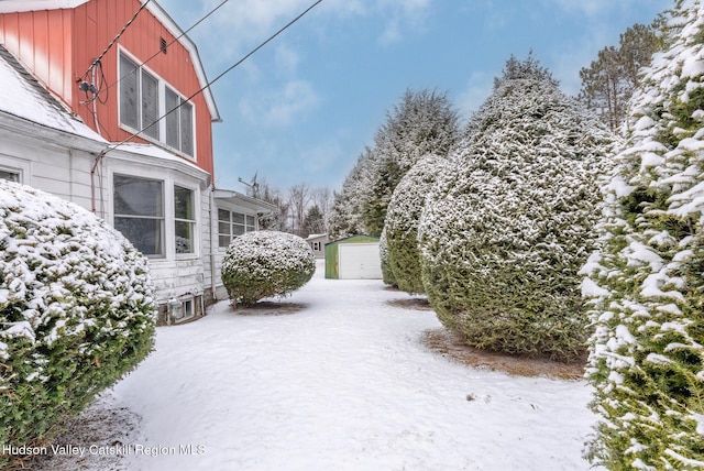 yard covered in snow with a garage and an outdoor structure