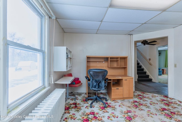 home office featuring a drop ceiling, ceiling fan, and radiator heating unit