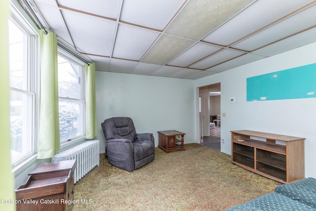 sitting room with a drop ceiling, carpet floors, and radiator