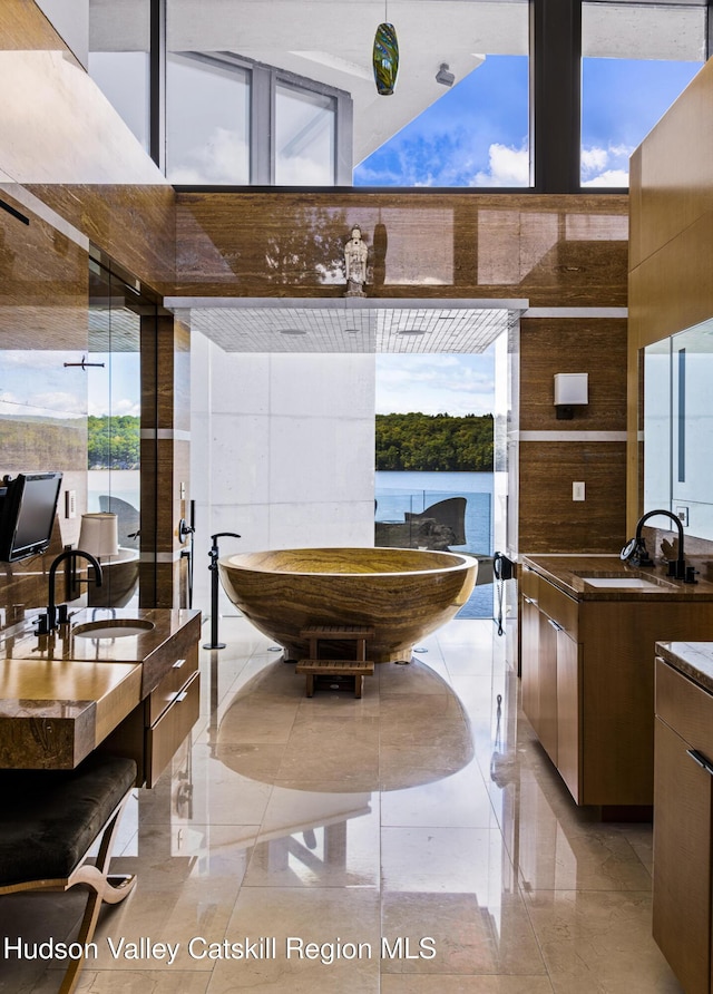 interior space featuring a high ceiling, a water view, and sink