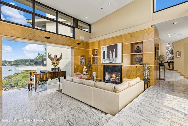 living room featuring a high ceiling, a water view, and a premium fireplace