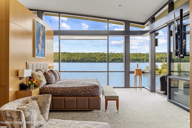 carpeted bedroom with access to exterior, a wall of windows, vaulted ceiling, wooden walls, and a water view