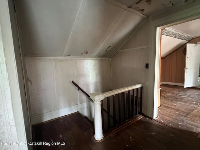 additional living space featuring wood walls, dark hardwood / wood-style flooring, and lofted ceiling