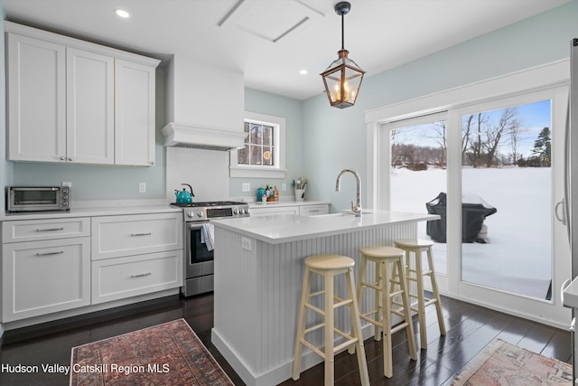 kitchen with white cabinets, a kitchen island with sink, hanging light fixtures, and stainless steel gas stove